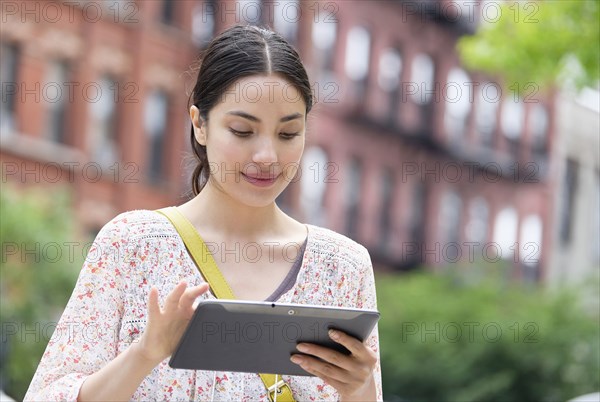 Hispanic woman using digital tablet in city