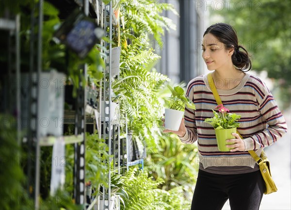 Hispanic woman shopping for plants in nursery