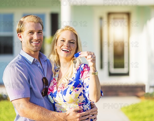 Caucasian couple holding keys outside new home