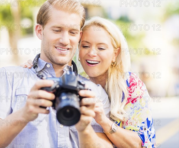 Caucasian couple reviewing digital photographs on camera
