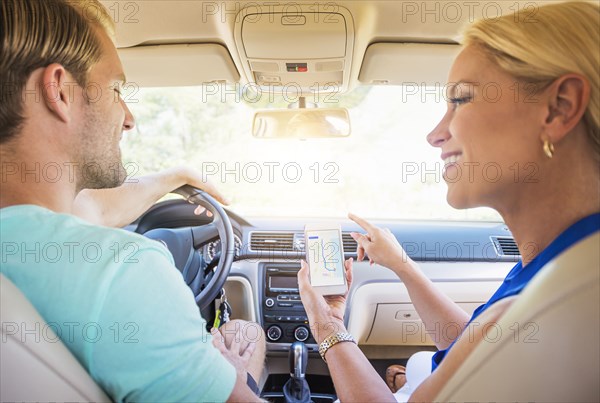 Caucasian couple using cell phone navigation in car