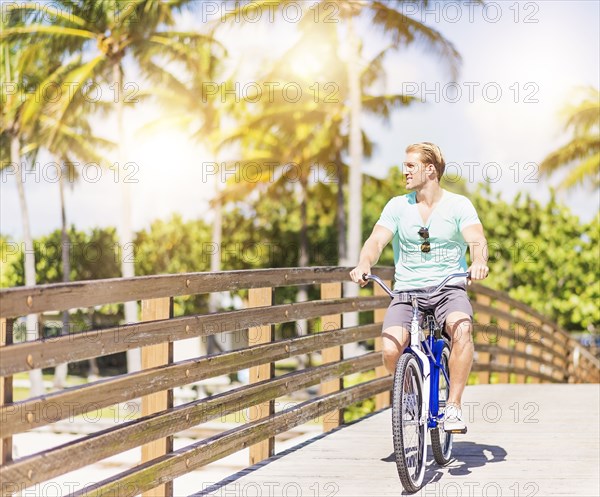 Caucasian man riding bicycle on bridge