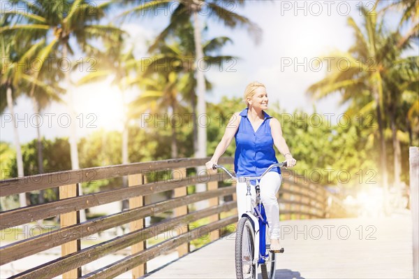 Caucasian woman riding bicycle on bridge