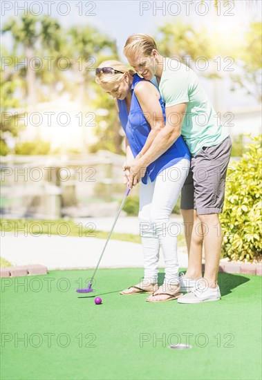 Caucasian couple playing miniature golf