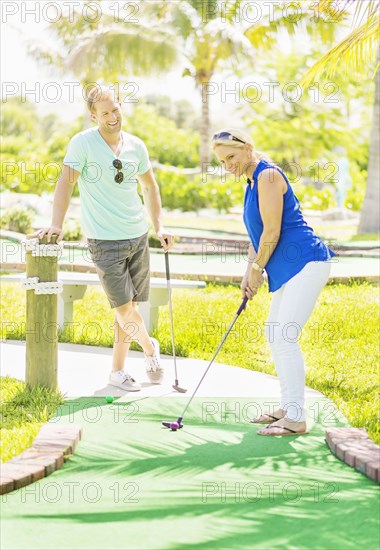 Caucasian couple playing miniature golf