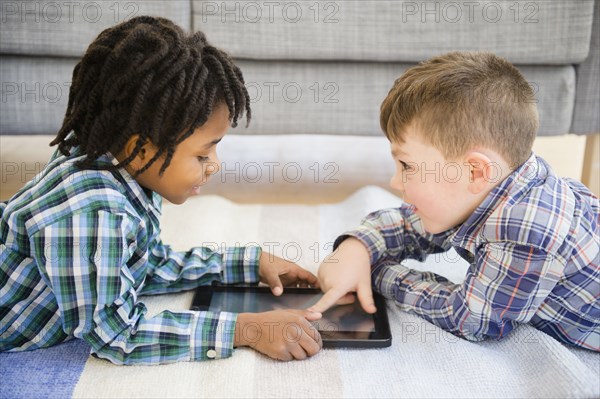 Boys playing with digital tablet on sofa