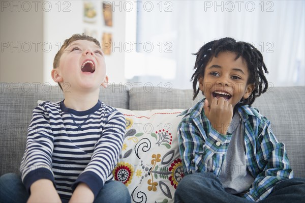 Boys laughing on living room sofa