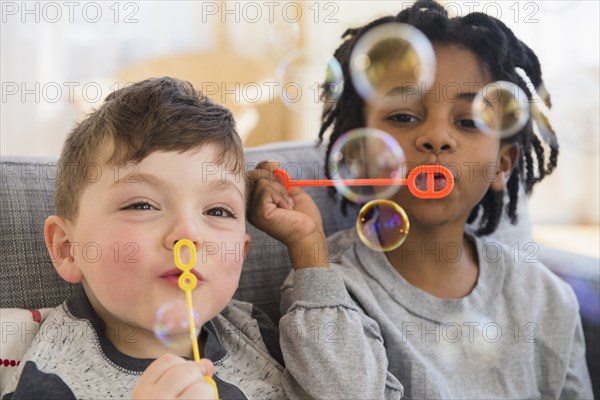 Close up of boys blowing bubbles on sofa