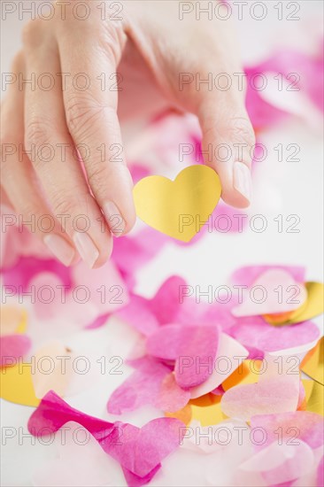 Mixed race woman holding confetti hearts