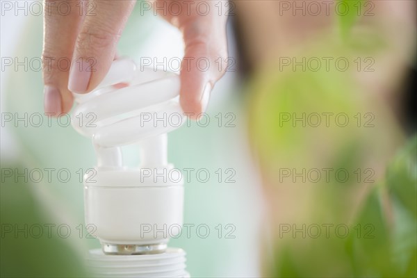 Mixed race woman holding fluorescent light bulb