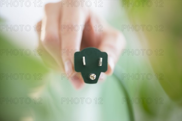 Mixed race woman holding electrical plug