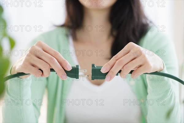 Mixed race woman plugging into extension cord