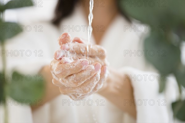 Mixed race woman washing her hands in water