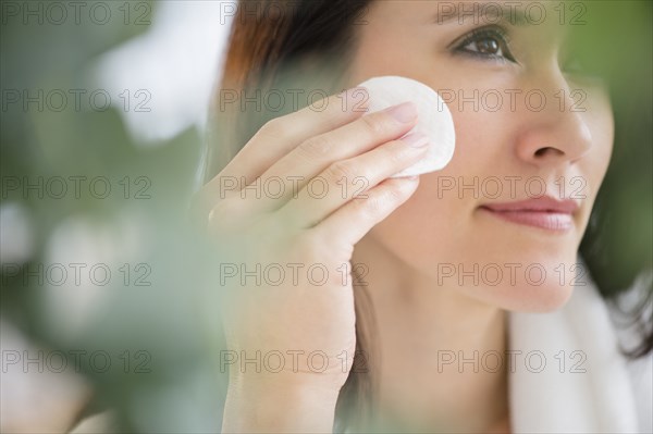 Mixed race woman patting makeup on face