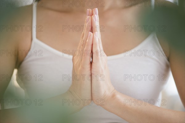 Mixed race woman meditating with clasped hands