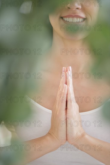 Mixed race woman meditating with clasped hands