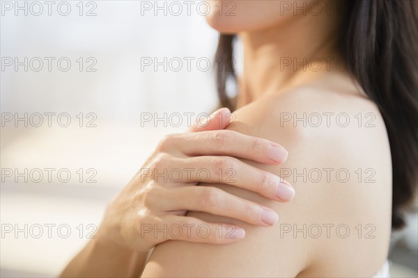 Mixed race woman rubbing lotion into skin