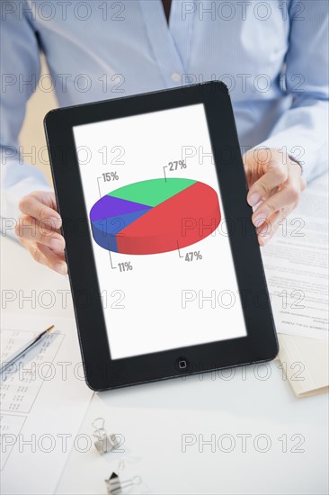 Mixed race businesswoman holding digital tablet with pie chart