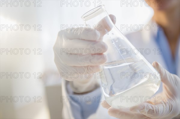 Mixed race scientist examining beaker in laboratory