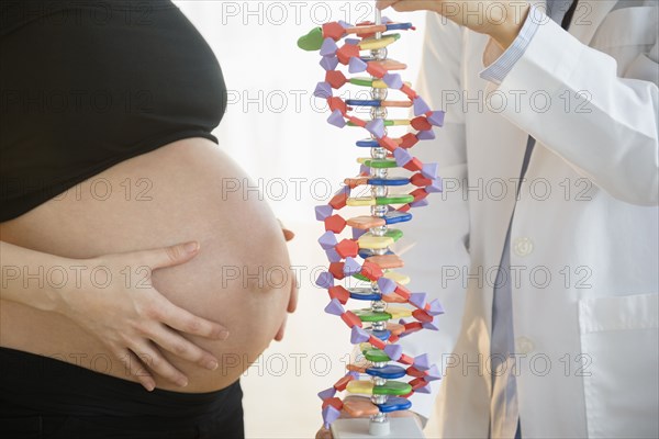 Pregnant woman and doctor examining DNA model