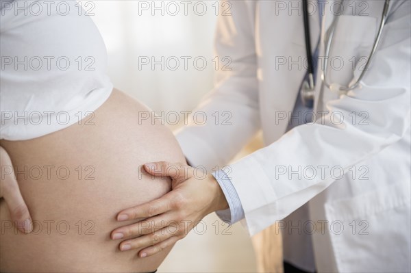 Doctor examining belly of pregnant woman