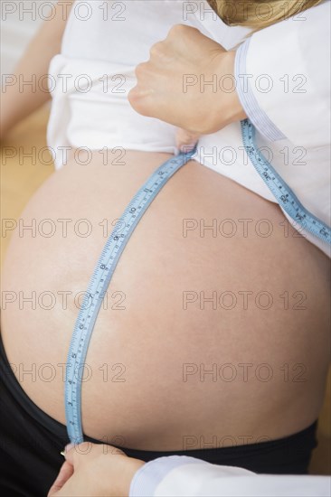 Doctor measuring belly of pregnant woman with measuring tape