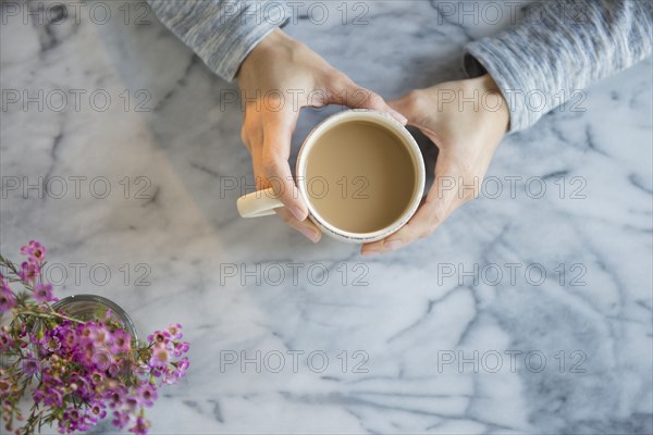 Mixed race woman drinking cup of coffee at table