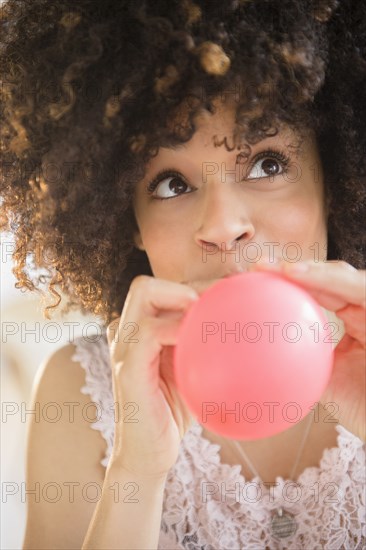 Mixed race woman inflating balloon