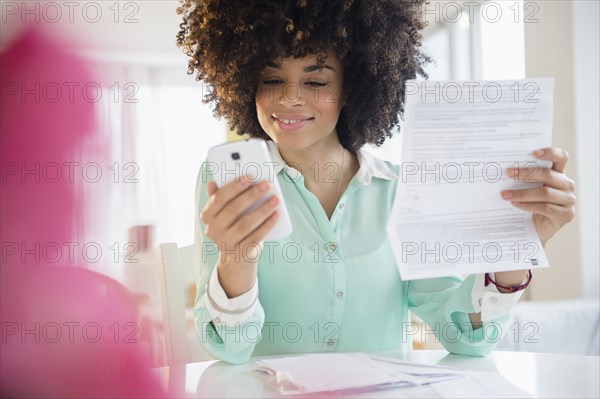 Mixed race woman paying bill with cell phone