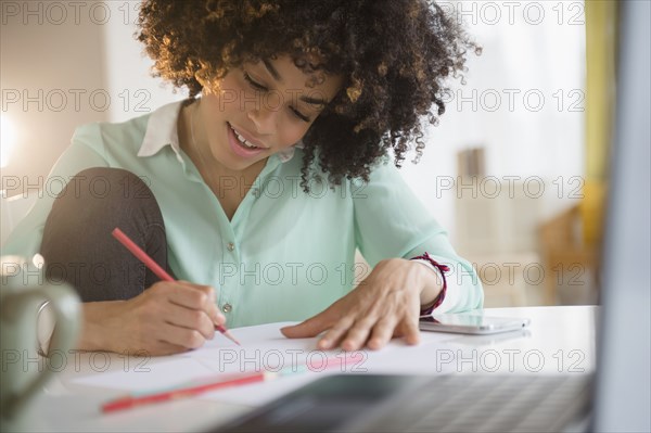 Mixed race student writing notes at desk