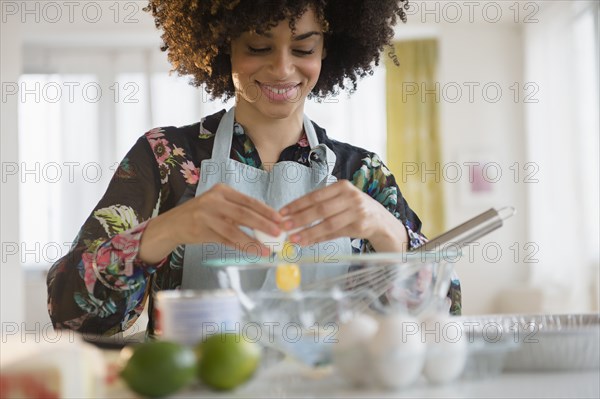 Mixed race woman cracking egg