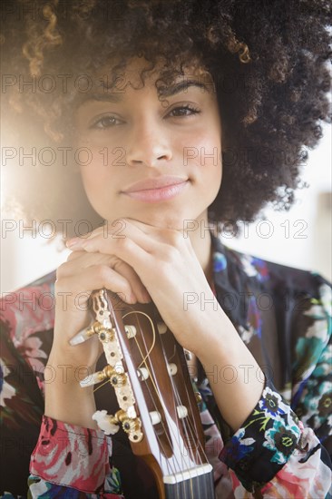 Mixed race musician holding guitar