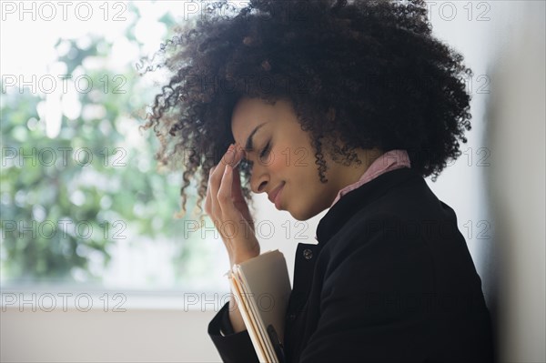 Stressed mixed race businesswoman rubbing her forehead