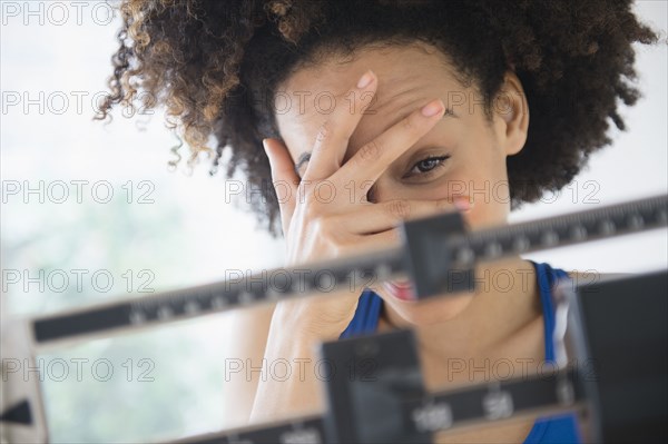 Mixed race woman hiding from weight on scale
