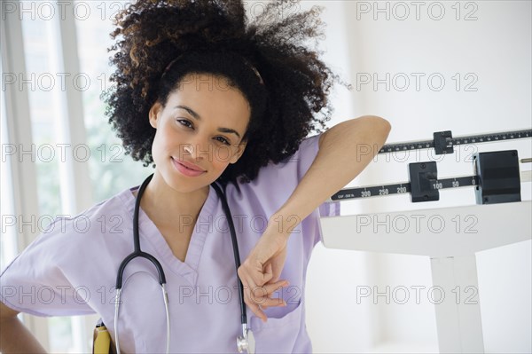 Mixed race nurse leaning on scale