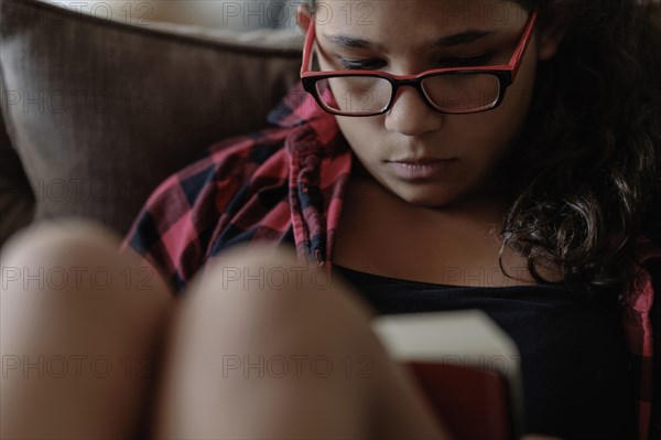 Mixed race girl reading on sofa