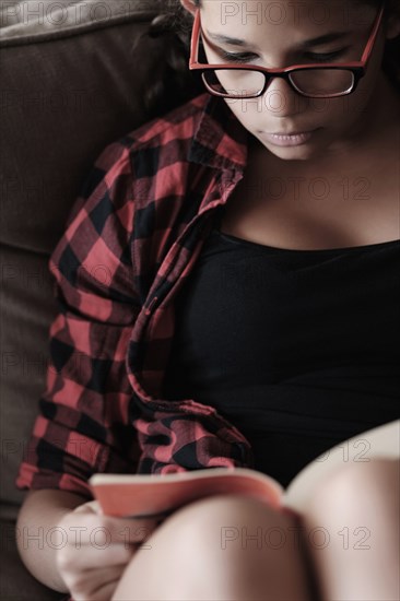 Mixed race girl reading on sofa