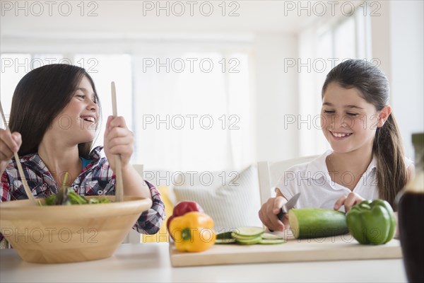 Caucasian twin sisters preparing salad