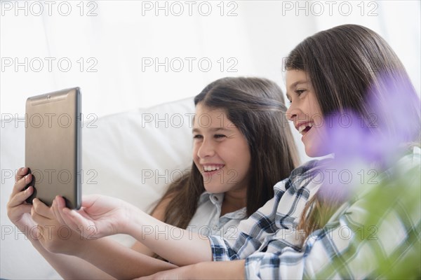 Caucasian twin sisters using digital tablet