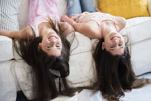 Caucasian twin sisters laying on sofa