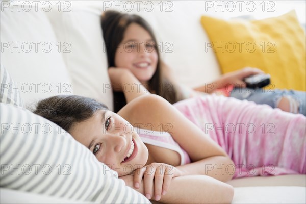 Caucasian twin sisters laying on sofa