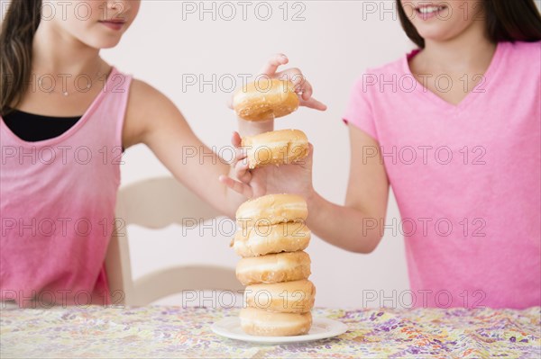 Caucasian twin sisters eating donuts