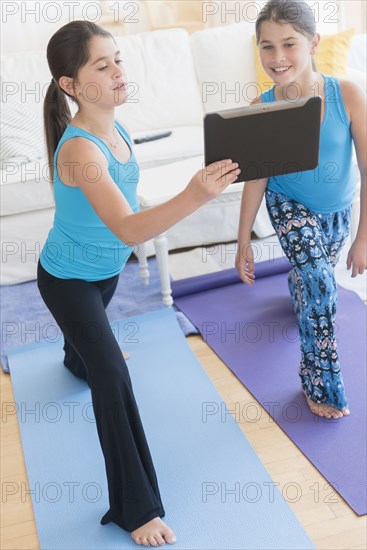 Caucasian twin sisters learning yoga with digital tablet