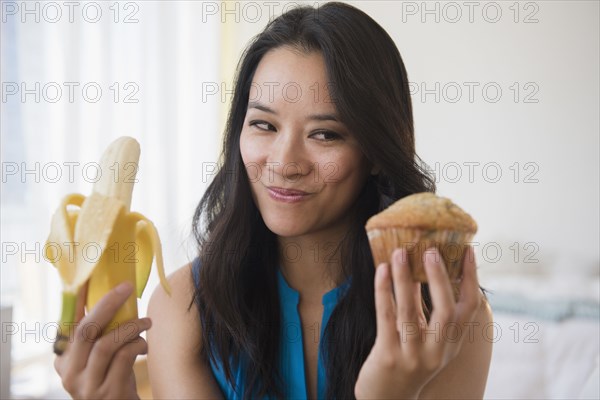 Chinese woman choosing between banana and muffin