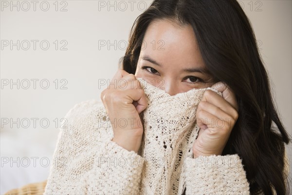 Chinese woman peeking over collar of sweater