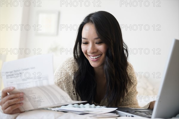 Chinese woman paying bills on laptop