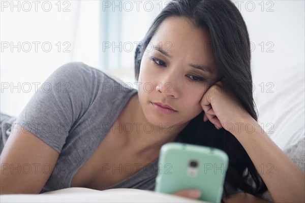 Chinese woman using cell phone on bed