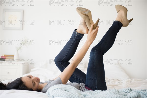 Chinese woman trying on shoes on bed