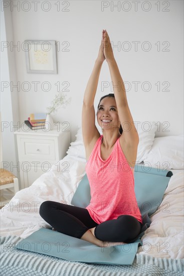 Chinese woman practicing yoga on bed