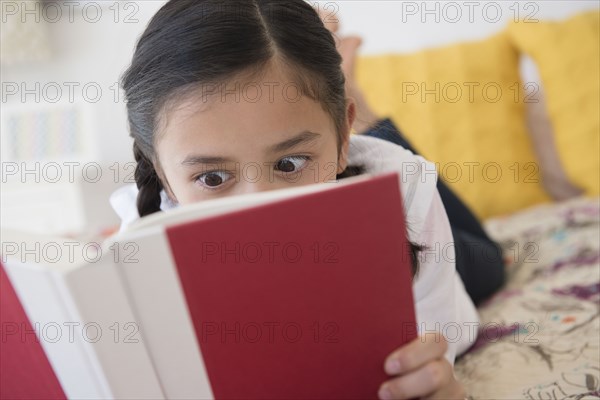 Girl reading book on bed